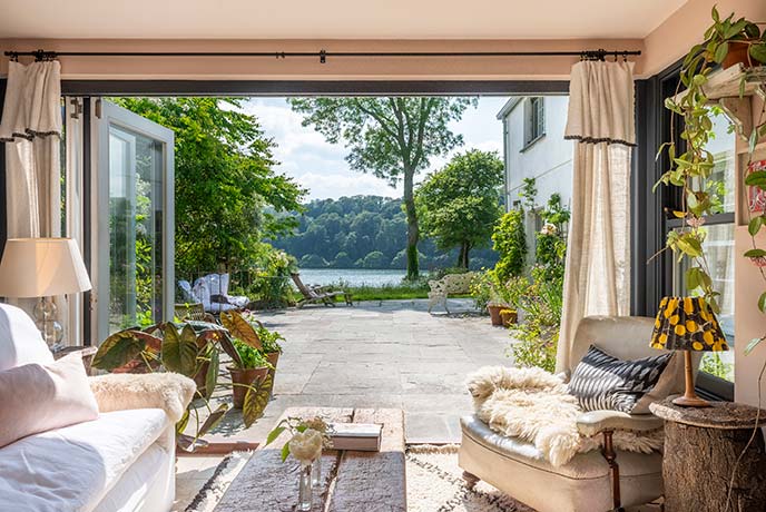 The beautiful living room with large open doors overlooking a courtyard and river at Penfoye in Cornwall