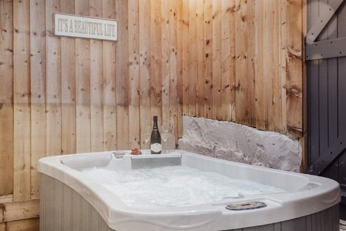 The hot tub in front of a panelled wall at Springtide