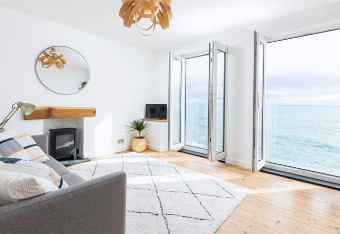 The spacious living room with huge open windows that look straight onto the sea in Porthleven