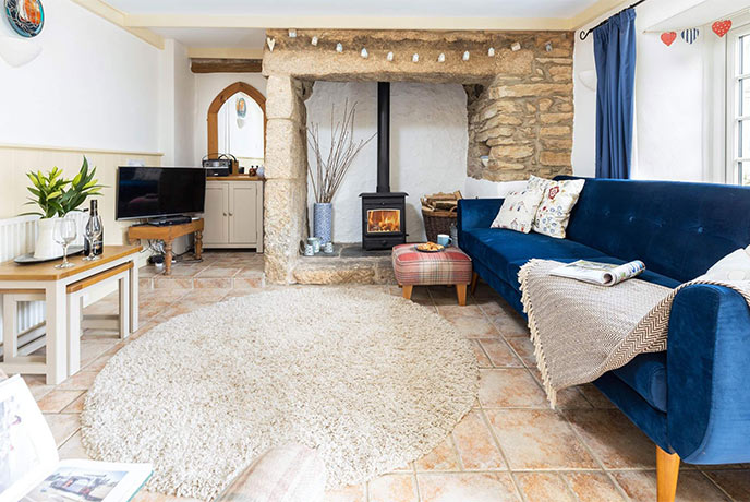 The cosy living room with a wood-burner and blue sofa at Smugglers Cottage