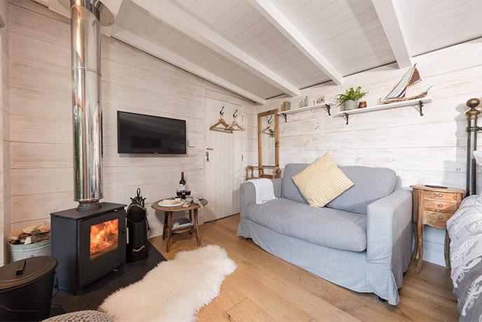 The cosy living area with a wood-burner and chair at Tree Tops Cabin