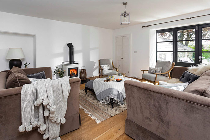 The spacious yet cosy living room at Well cottage with two sofas and a wood-burner