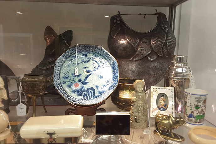 A glass display case full of antique at The Past and Present Emporium in Cornwall