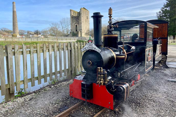 A steam train in front of an engine house at Lappa Valley