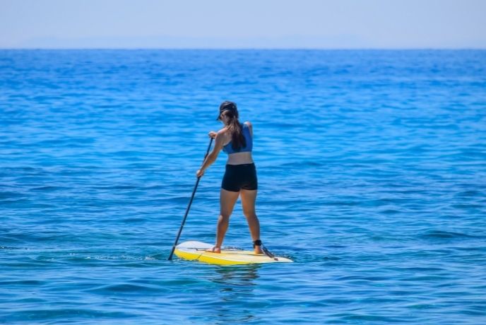 A woman paddleboarding in Cornwall