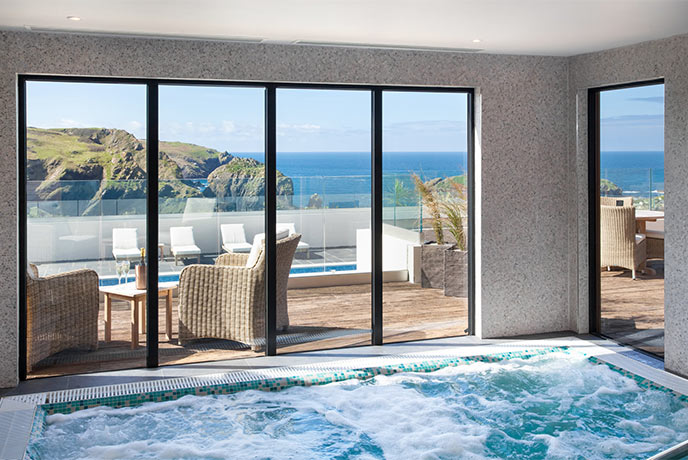 A hot tub next to decking that looks out over the ocean at Mullion Cove Spa