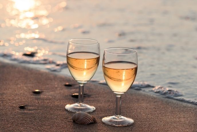 Two glasses of wine on the beach along the shoreline