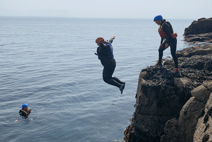 A member of the team doing the first jump of the day while coasteering with Global Boarders in Mousehole