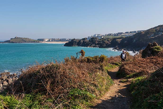 Someone walking along a coast path with St Ives in the background