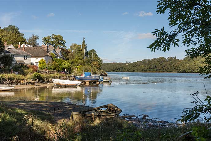 Looking across a river at thatched cottages in St Clement near Truro