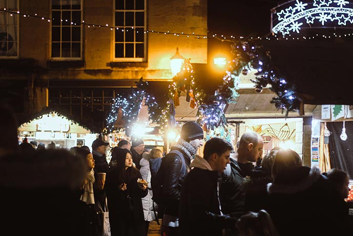 People shopping around stalls at the Bath Christmas Market at night