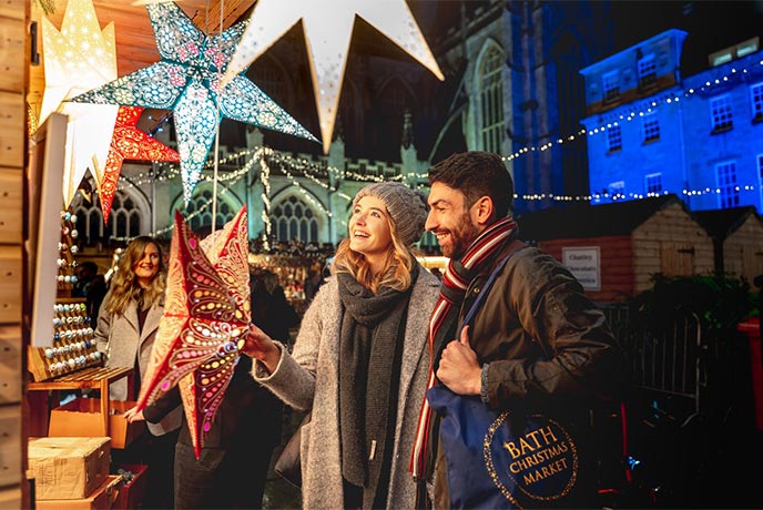 Two people looking at a stall selling decorative stars at Bath Christmas Market in the Cotswolds