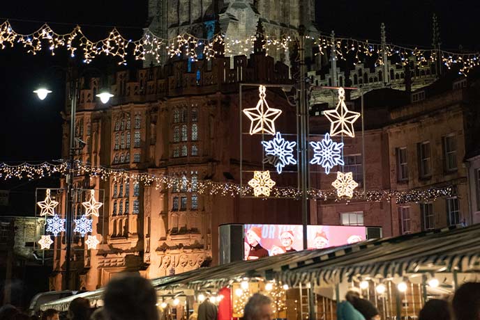 Beautiful Christmas lights hanging above stalls at the Cirencester Advent Market at Christmas in the Cotswolds