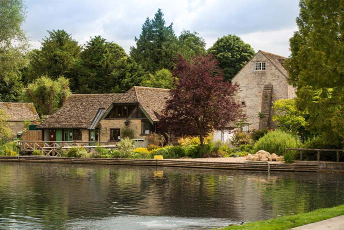 The beautiful Cotswold stone exterior of Bibury Trout Farm surrounded by trees