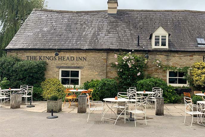 A selection of outdoor seating in front of the historic King's Head Inn in the Cotswolds