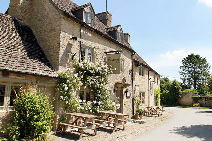 The pretty, golden-stone Maytime Inn in the Cotswolds with tables and chairs outside