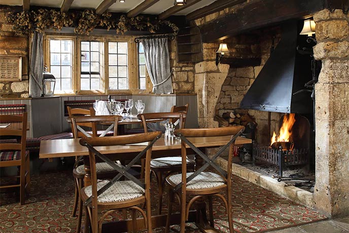 A cosy dining area with a wood burner at The Eight Bells Inn in the Cotswolds