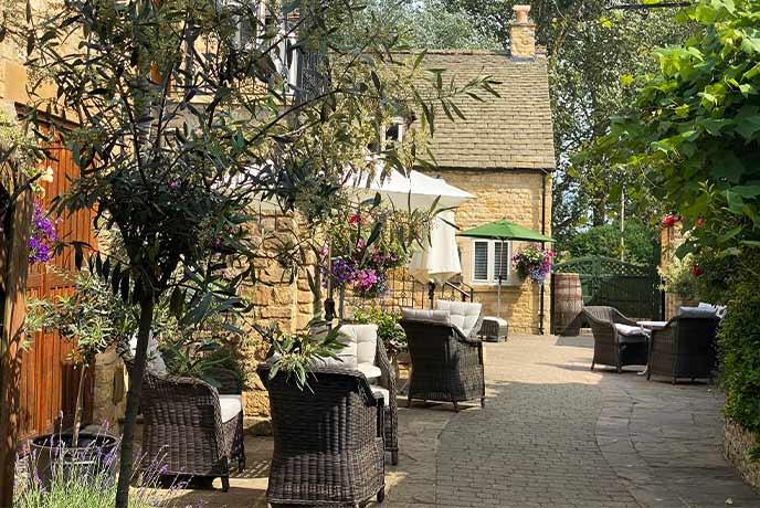 A golden stone courtyard with outdoor seating at The Lygon Arms in the Cotswolds
