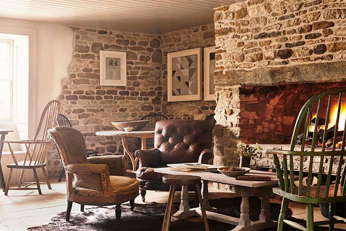 The cosy pub dining room with a roaring fire at The Wild Rabbit in the Cotswolds