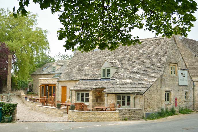 The traditional, gold-stone exterior of The Plough Inn in the Cotswolds