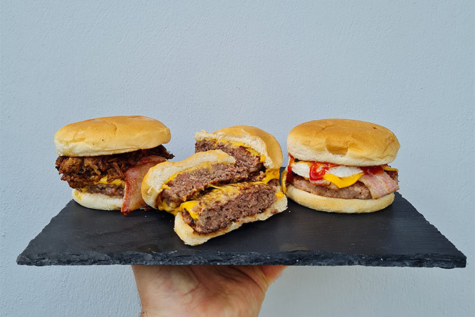 Three breakfast burgers held up on a slate platter at Frocester Fayre Farm Shop