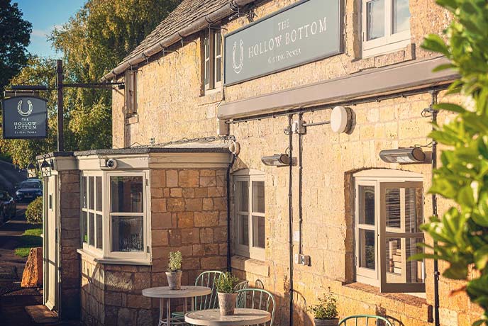 The golden-bricked exterior of The Hollow Bottom pub in the Cotswolds