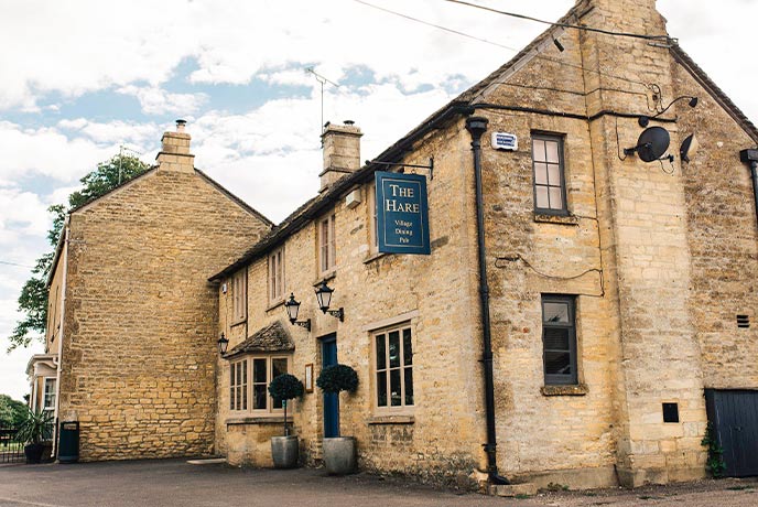 The golden stone exterior of The Hare in the Cotswolds
