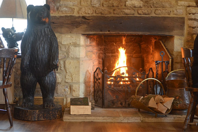 A fireplace surrounded by statues of black bears at The Black Bear Inn in the Cotswolds