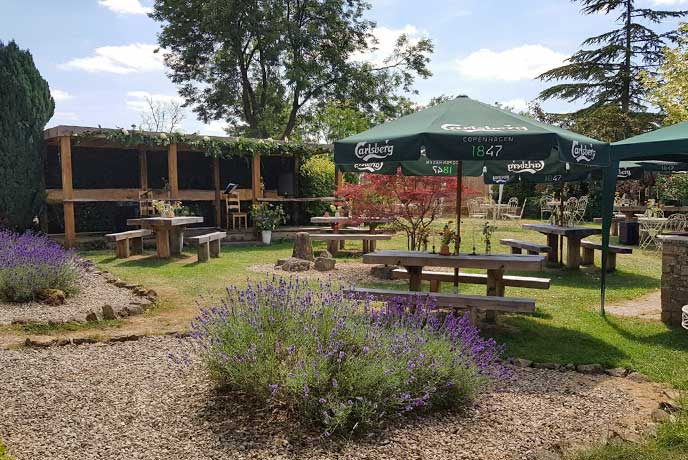 A sunny pub garden with flowers and outdoor seating at The Red Lion in the Cotswolds