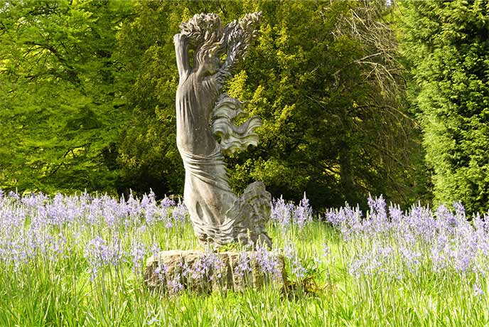 Bluebells surrounding a sculpture at Batsford Arboretum in the Cotswolds