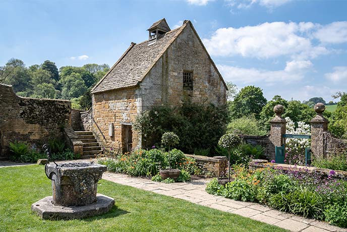 A pretty building surrounded by flowers at Snowshill Manor and Garden in the Cotswolds