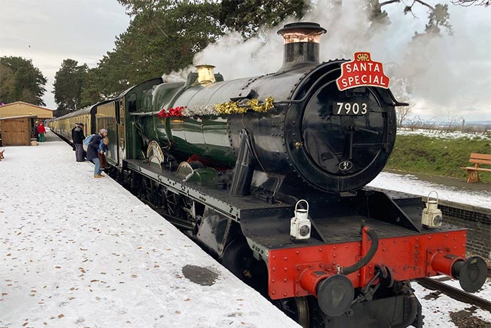 A train and platform covered in a layer of snow at Gloucestershire Warwickshire Railway in the Cotswolds