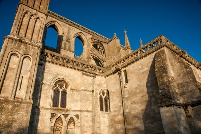Looking up at Malmesbury Abbey with blue sky above