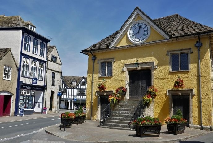 A beautiful old yellow building with a clock in Tetbury