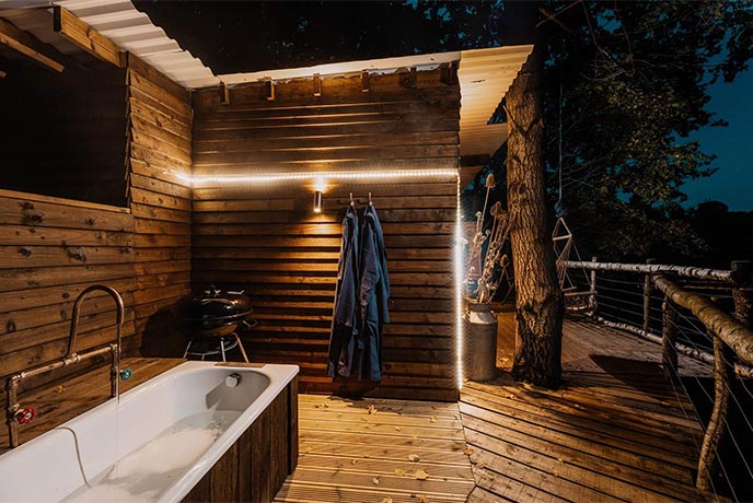 The incredible wooden terrace and outdoor bathtub at Tawny Owl Treehouse in Cumbria