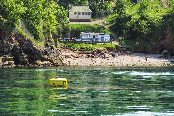 Looking across the turquoise water at Fishcombe Cove with Fishcombe Cove Cafe perched above