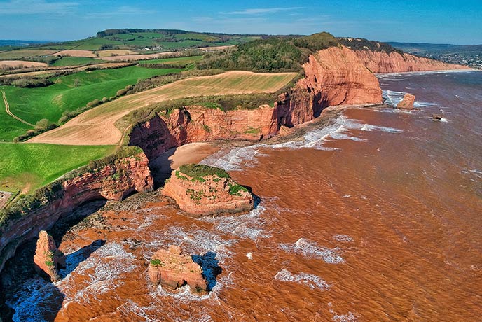 A bird's eye view of the incredible, red sandstone cliffs at Ladram Bay, one of the best beaches in Devon