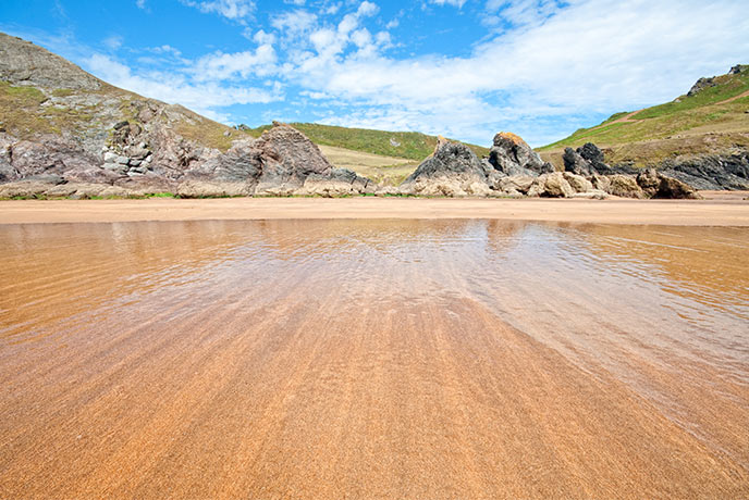 Looking up the sands at the beautiful beach and cliffs at Soar Mill Cove in Devon