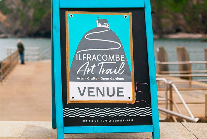 A brightly coloured sign for the Ilfracombe Art Trail on a harbour