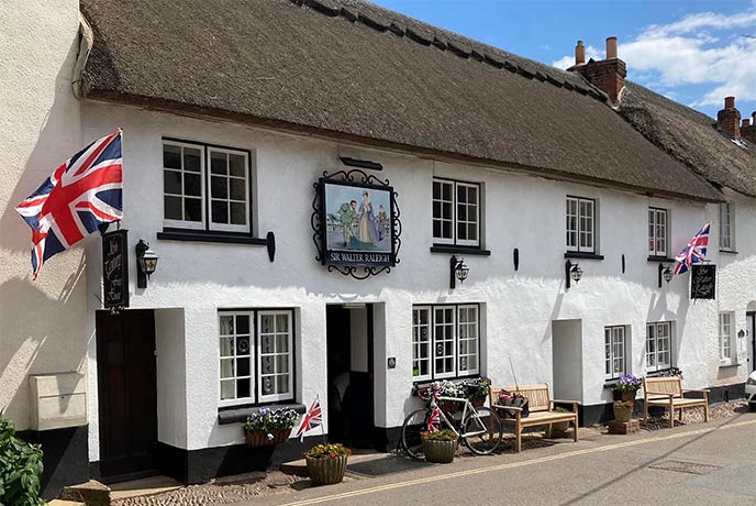 The white walled and thatched exterior of The Sir Walter Raleigh pub in Devon