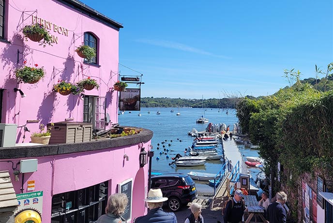 The bright pink exterior of The Ferry Boat Inn with the sea in the background