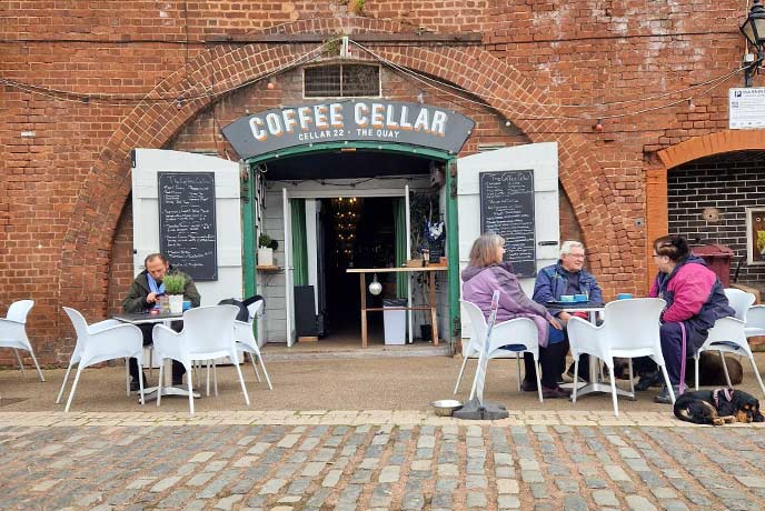 People sitting outside the red bricked Coffee Cellar café in Exeter