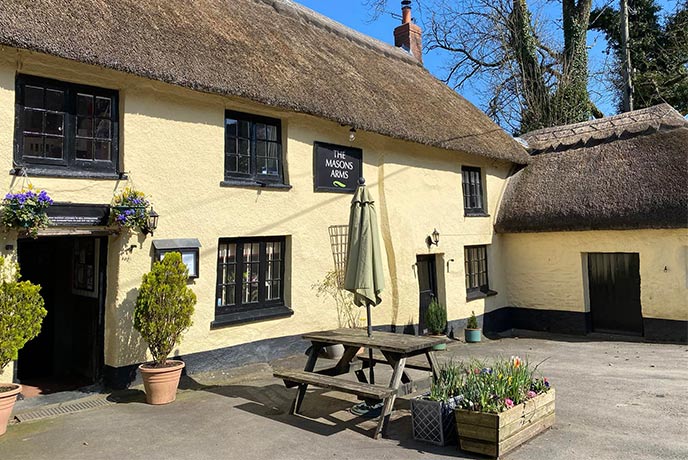 The quaint, yellow and thatched exterior of The Mason's Arms