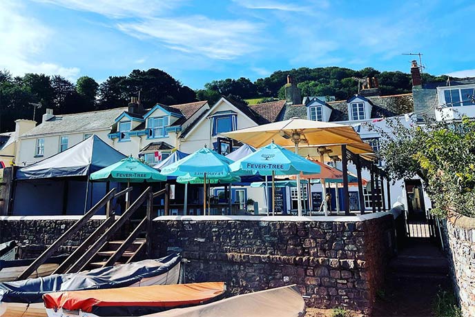 The Ferry Boat Inn sits directly above the beach where kayaks sit in the sand and parasols in the beer garden provide shade from the sun