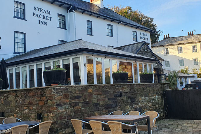 The white exterior of The Steam Packet Inn with tables and chairs outside for some al fresco dining