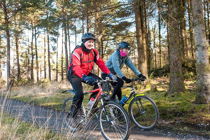 Two people cycling through Haldon Forset Park in Devon