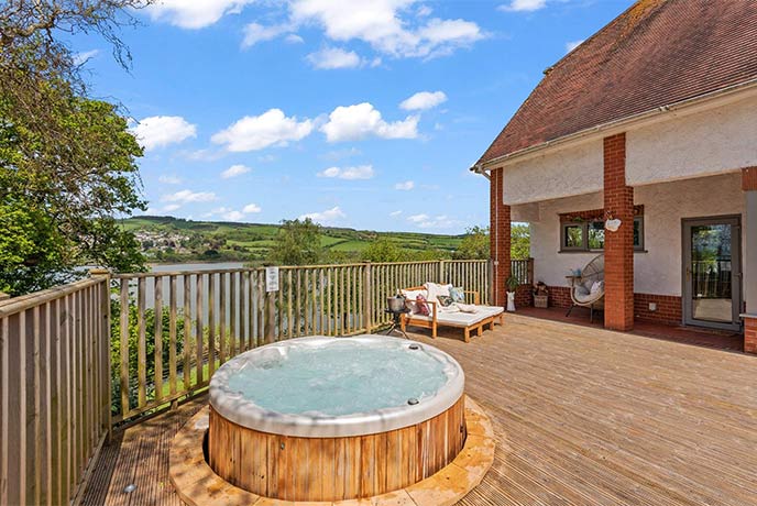 The waterside terrace and hot tub at Meadowcliff in Devon