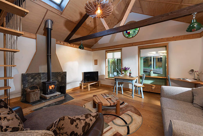 The cosy living area at Straw Cottage with high ceilings and a wood-burner