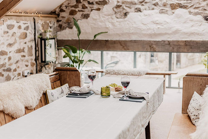 The rustic dining table and exposed stone walls at Widgery in Devon