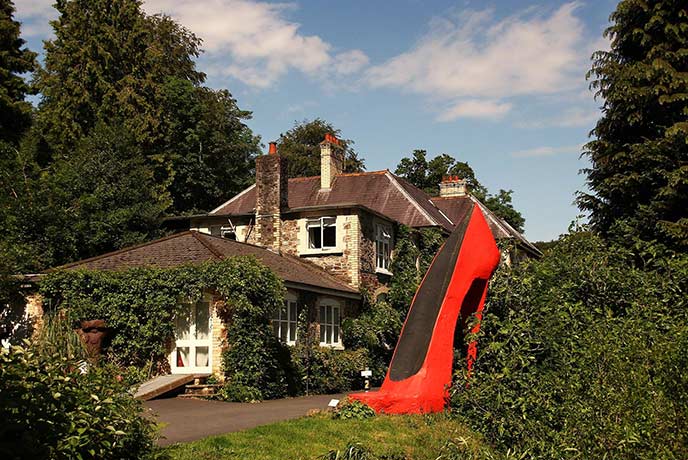 The traditional exterior of Broomhill Estate with a huge red heel installation in the garden